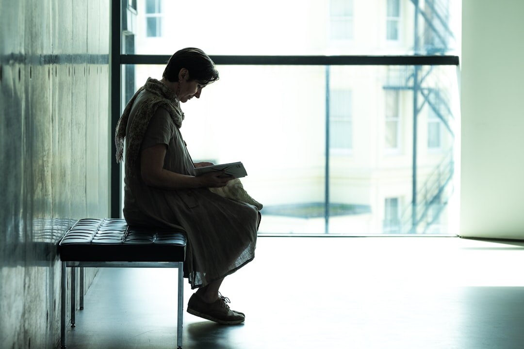 Woman reading a detective novel intently by a window